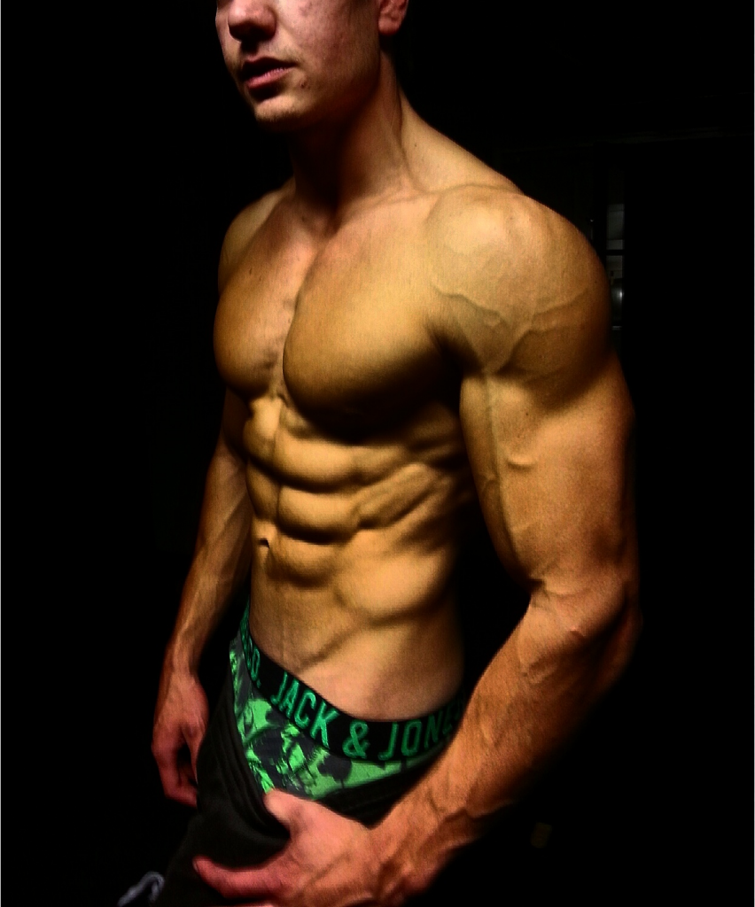 Muskulös man med sexpack och synliga ådror på armen.